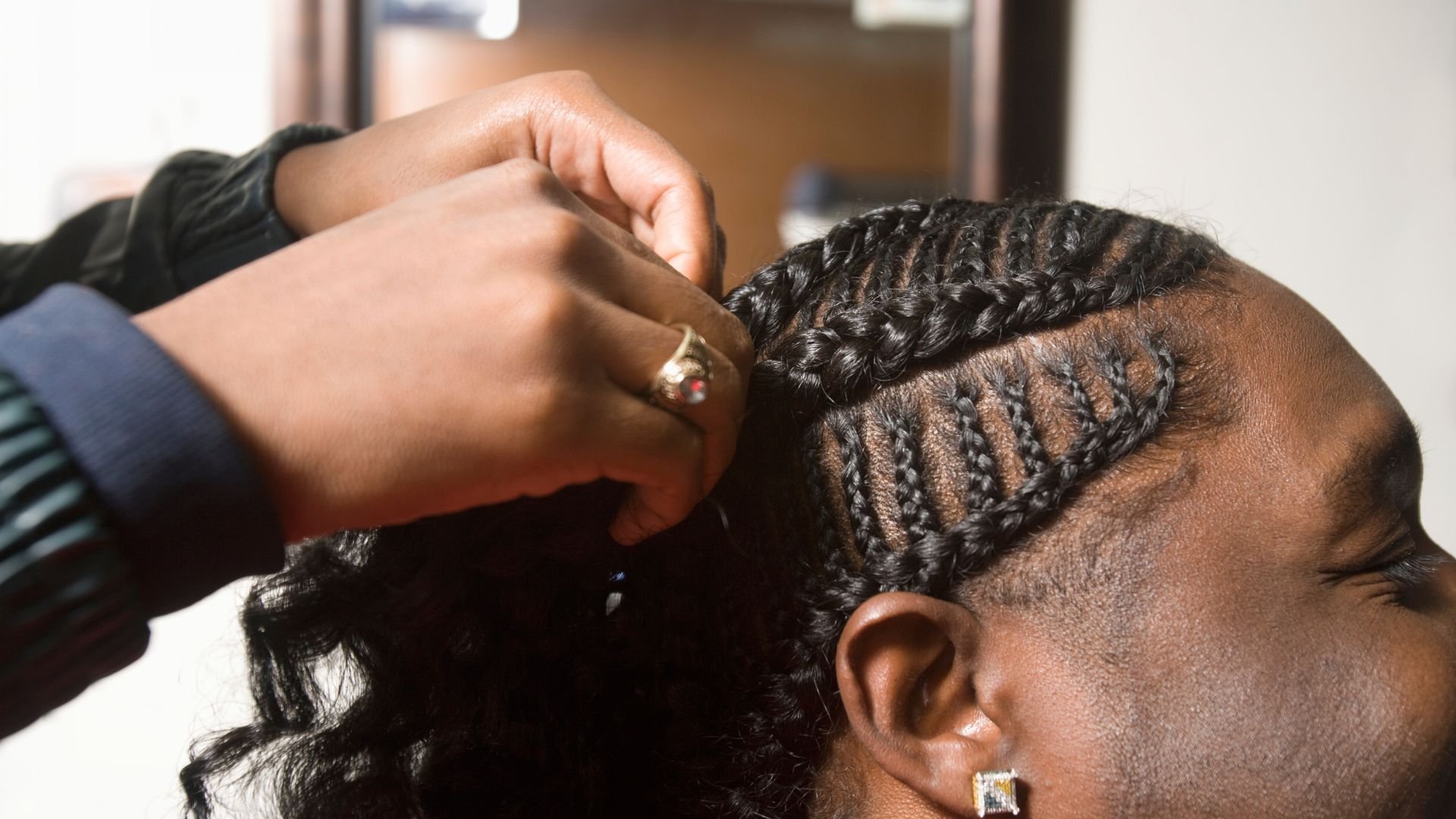 Hands styling intricate braids in someone's hair close-up