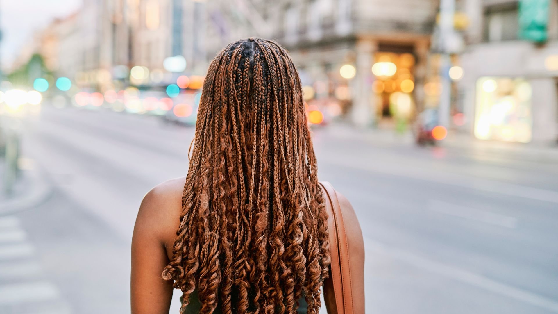 Back view of person with long braided hair in city street