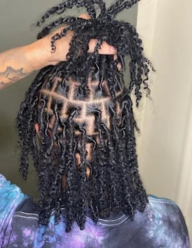 Intricate black loc hairstyle with curly ends and detailed root pattern