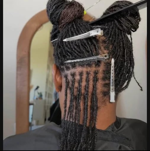 Dreadlocks being sectioned and styled with hair clips in salon
